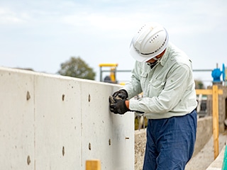 コンクリート壁に電動工具で作業する現場作業員。土木工事の作業風景